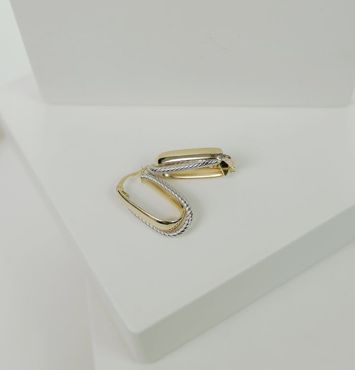Stylish gold and silver earrings showcased on a minimalist white platform, perfect for fashion enthusiasts.